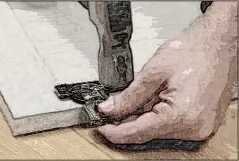 Tapping a hinge into the bored hole of a cabinet door with a hammer